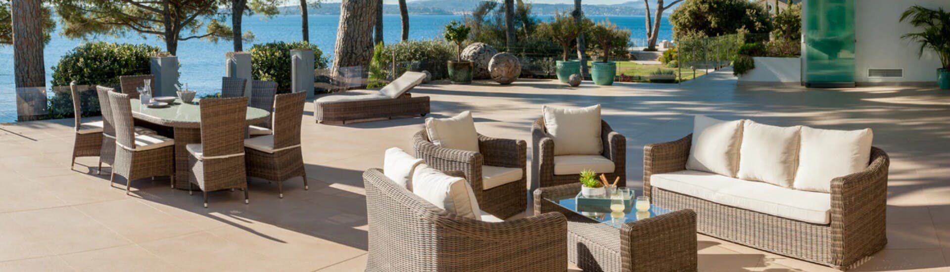 Une terrasse ensoleillée avec vue sur mer et de nombreux mobiliers de jardin