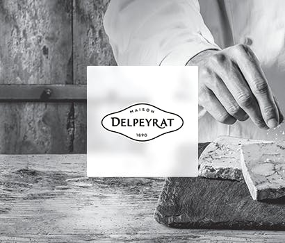 Logo Delpeyrat avec en fond une main cuisinant sur un plan de travail