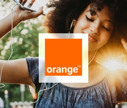 Logo Orange devant la photo d'une femme écoutant de la musique avec son smartphone