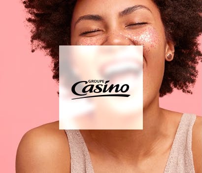 Logo Groupe Casino devant photo d'une femme souriante sur fond rose